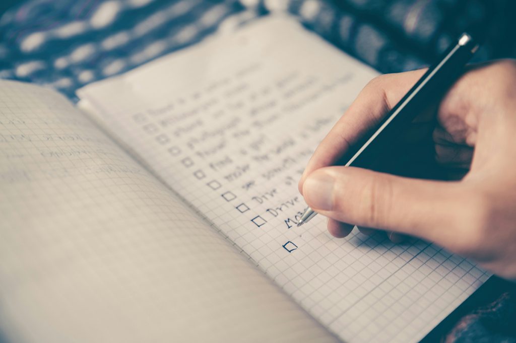 person writing a to-do list in a planner