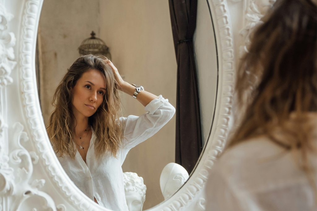 woman looking at her own reflection in mirror